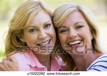 Two women outdoors embracing and smiling View Large Photo Image Stock Image - Two women outdoors embracing and smiling. Fotosearch