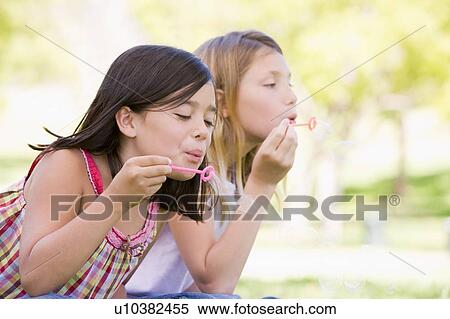 Two young girls blowing bubbles outdoors View Large Photo Image Stock Photography - Two young girls blowing bubbles outdoors. Fotosearch