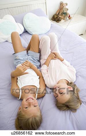 Two Young Girls In Their Pajamas Lying On A Bed View Large Photo Image Stock Image - Two Young Girls In Their Pajamas Lying On A Bed. Fotosearch