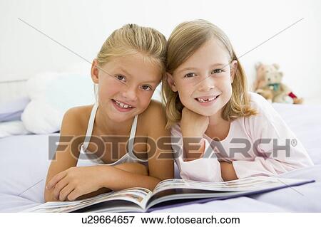 Two Young Girls In Their Pajamas, Reading A Book View Large Photo Image Stock Photo - Two Young Girls In Their Pajamas, Reading A Book. Fotosearch