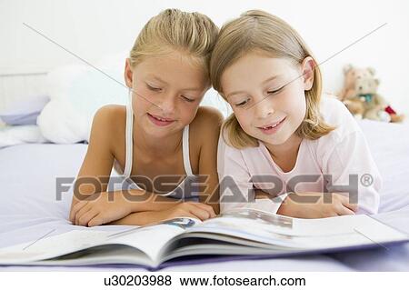 Two Young Girls In Their Pajamas, Reading A Book View Large Photo Image Stock Photo - Two Young Girls In Their Pajamas, Reading A Book. Fotosearch