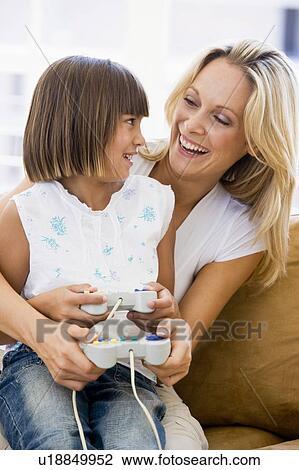 Woman and young girl in living room with video game controllers smiling View Large Photo Image Stock Image - Woman and young girl in living room with video game controllers smiling. Fotosearch