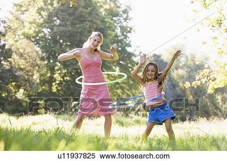 Woman and young girl outdoors using hula hoops and smiling View Large Photo Image Stock Photography - Woman and young girl outdoors using hula hoops and smiling. Fotosearch