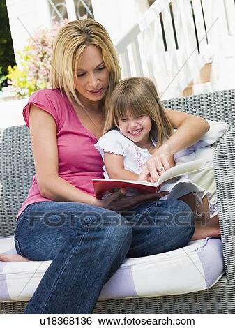 Woman and young girl sitting on patio reading book smiling View Large Photo Image Stock Photograph - Woman and young girl sitting on patio reading book smiling. Fotosearch