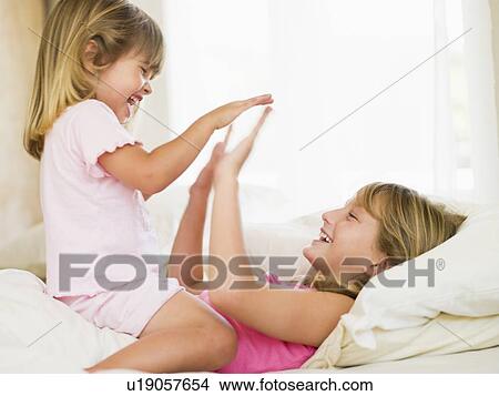 Picture - Young Girl Being Woken Up By Her Little Sister. Fotosearch