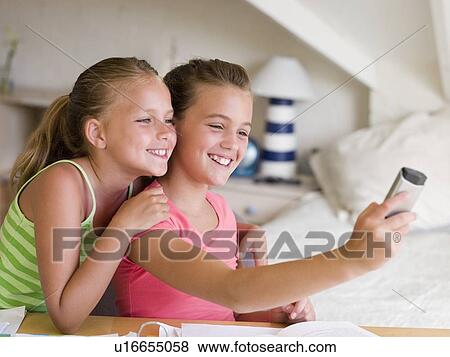 Young Girls Distracted From Their Homework, Playing With A Cellphone View Large Photo Image Stock Photo - Young Girls Distracted From Their Homework, Playing With A Cellphone. Fotosearch