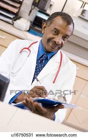 A Doctor Writing On A Clipboard At The Reception Area Of A Hospital View Large Photo Image Stock Image - A Doctor Writing On A Clipboard At The Reception Area Of A Hospital. Fotosearch