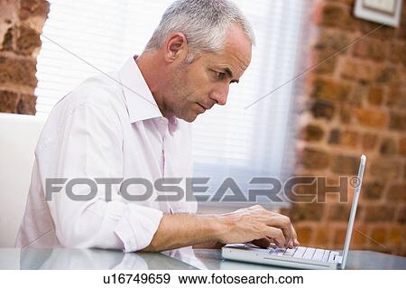 Stock Photo - Businessman sitting in office typing on laptop. Fotosearch