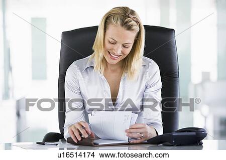 Picture - Businesswoman in office looking at personal organizer smiling. Fotosearch