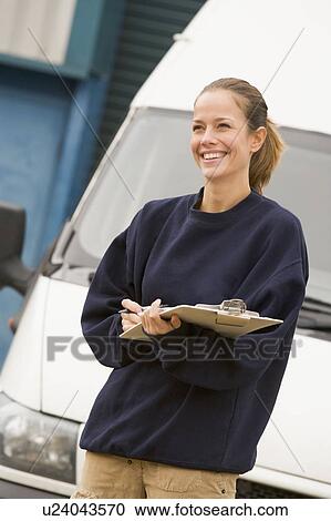 Deliveryperson standing with van writing in clipboard smiling View Large Photo Image Stock Image - Deliveryperson standing with van writing in clipboard smiling. Fotosearch