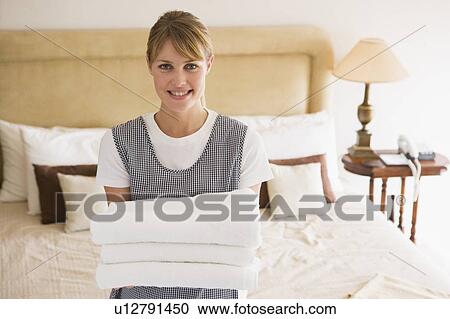 Maid holding towels in hotel room smiling View Large Photo Image Stock Image - Maid holding towels in hotel room smiling. Fotosearch