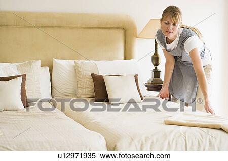 Maid making bed in hotel room View Large Photo Image Stock Photography - Maid making bed in hotel room. Fotosearch