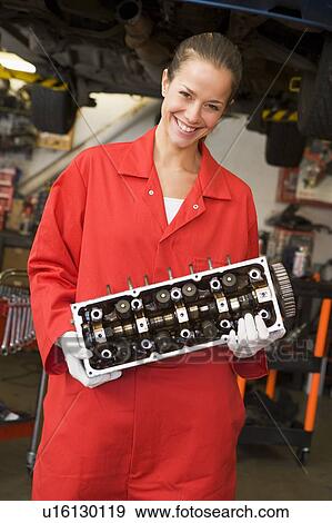 Stock Photo - Mechanic holding car part smiling. Fotosearch