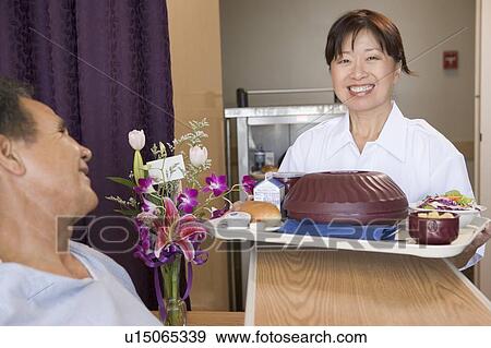 Stock Photo - Nurse Serving A Patient A Meal In His Bed. Fotosearch