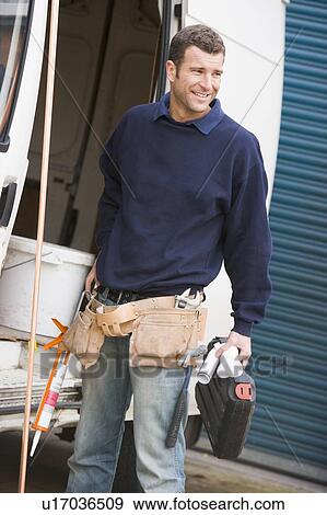 Stock Photo - Plumber standing with van smiling. Fotosearch
