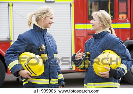 Two firewomen standing by fire engine talking View Large Photo Image Stock Photography - Two firewomen standing by fire engine talking. Fotosearch