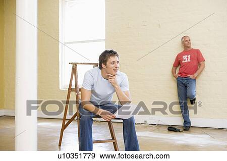 Two men with ladder in empty space one holding paper smiling View Large Photo Image Stock Photo - Two men with ladder in empty space one holding paper smiling. Fotosearch