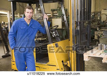 Stock Photography - Warehouse worker standing by forklift. Fotosearch