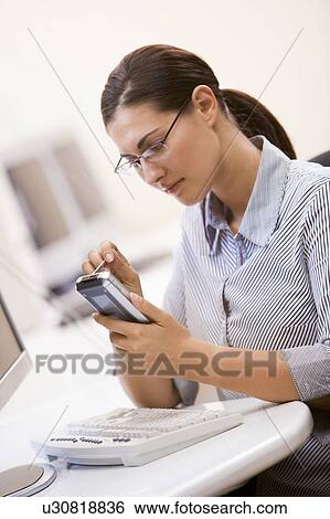 Woman in computer room using personal digital assistant View Large Photo Image Stock Photograph - Woman in computer room using personal digital assistant. Fotosearch