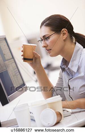 Stock Photo - Woman in computer room with many cups of empty coffee around her. Fotosearch