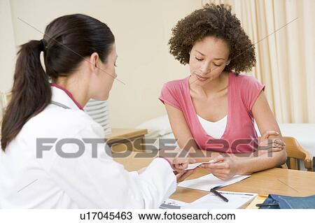 Stock Image - Woman in doctor's office frowning. Fotosearch
