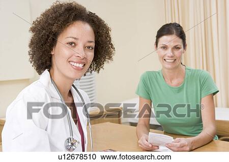 Stock Image - Woman in doctor's office smiling. Fotosearch