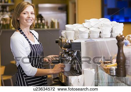Stock Image - Woman making coffee in restaurant smiling. Fotosearch