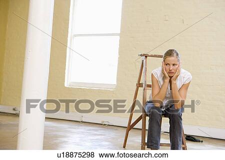 Woman sitting on ladder in empty space looking bored View Large Photo Image Stock Photo - Woman sitting on ladder in empty space looking bored. Fotosearch