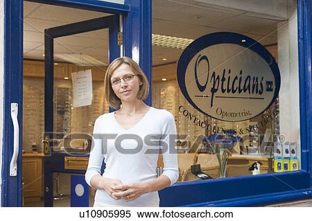 Stock Photography - Woman standing at front entrance of optometrists. Fotosearch