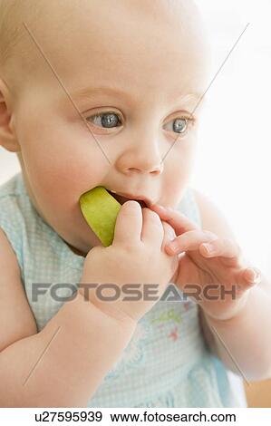 Baby eating apple indoors View Large Photo Image Stock Photo - Baby eating apple indoors. Fotosearch