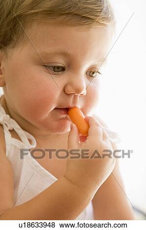 Baby indoors eating carrot. View Large Photo Image Stock Photo - Baby indoors eating carrot.. Fotosearch