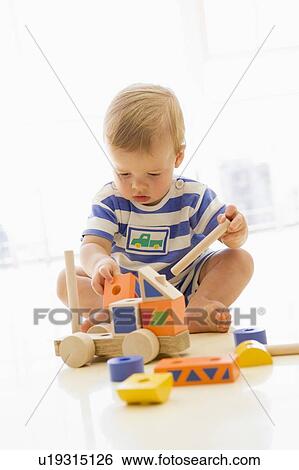 Baby indoors playing with truck View Large Photo Image Stock Photograph - Baby indoors playing with truck. Fotosearch