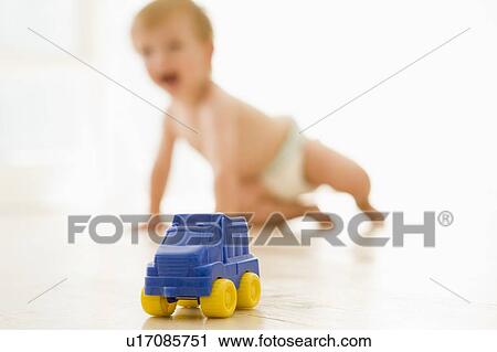 Stock Image - Baby indoors with toy truck. Fotosearch