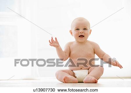 Stock Image - Baby sitting indoors smiling. Fotosearch