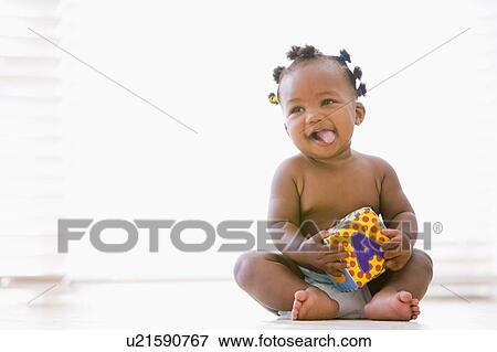 Baby sitting indoors with block smiling View Large Photo Image Stock Photo - Baby sitting indoors with block smiling. Fotosearch