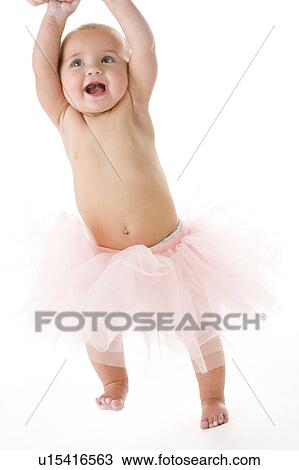 Stock Image - Baby standing in tutu. Fotosearch