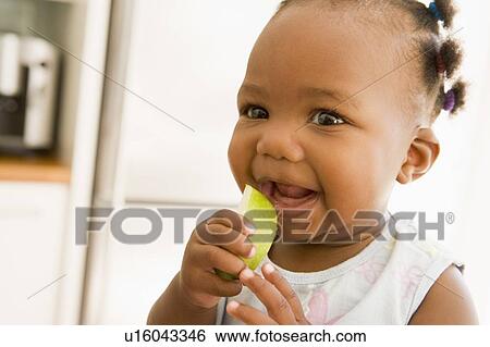 Young girl eating apple indoors View Large Photo Image Stock Photograph - Young girl eating apple indoors. Fotosearch