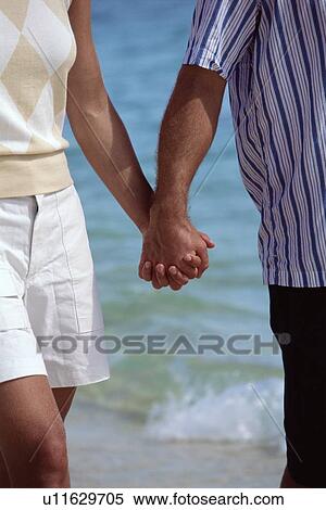 Stock Photography - Couple holding hands outdoors at the beach (selective focus). Fotosearch