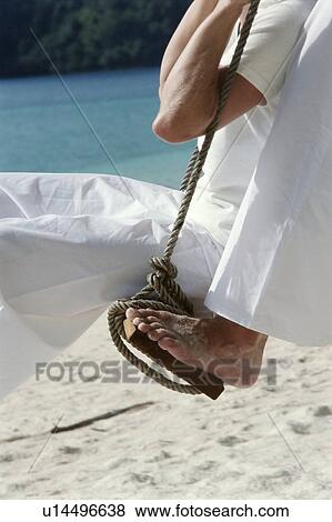 Stock Photo - Couple on a swing outdoors at the beach (selective focus). Fotosearch