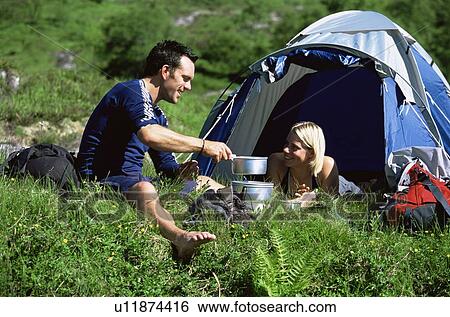 Stock Photograph - Couple outdoors at campsite with pots smiling (selective focus). Fotosearch