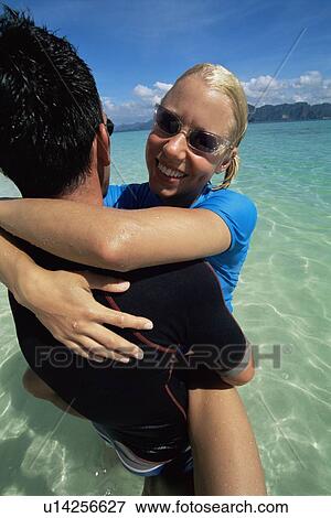 Couple outdoors embracing at beach and smiling View Large Photo Image Stock Photo - Couple outdoors embracing at beach and smiling. Fotosearch