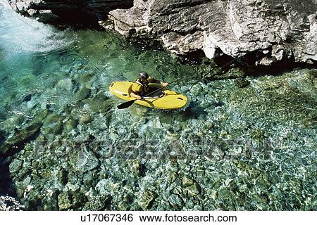 Kayaker in calm water near large rocks View Large Photo Image Stock Photograph - Kayaker in calm water near large rocks. Fotosearch