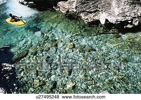 Stock Photo - Kayaker outdoors sitting in small kayak in water (selective focus). Fotosearch