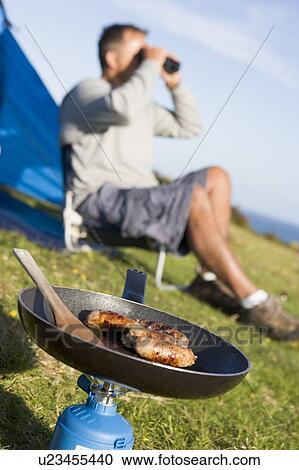 Man camping outdoors and cooking View Large Photo Image Stock Image - Man camping outdoors and cooking. Fotosearch