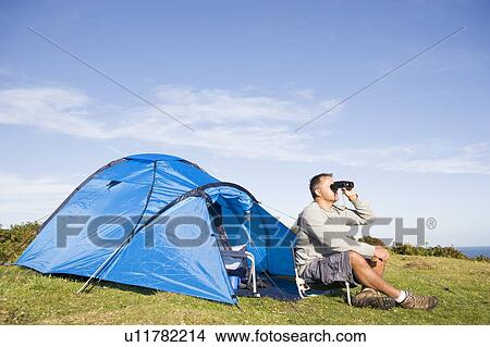 Man camping outdoors and looking through binoculars View Large Photo Image Picture - Man camping outdoors and looking through binoculars. Fotosearch
