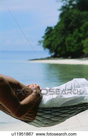 Man in a hammock outdoors on the beach (selective focus) View Large Photo Image Stock Photo - Man in a hammock outdoors on the beach (selective focus). Fotosearch