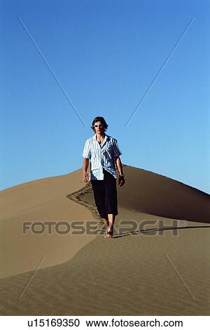 Stock Image - Man outdoors walking in the desert. Fotosearch