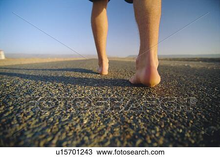 Stock Image - Man's feet on a path outdoors (selective focus). Fotosearch