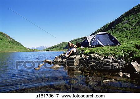 Woman at campsite sitting near river View Large Photo Image Stock Photo - Woman at campsite sitting near river. Fotosearch