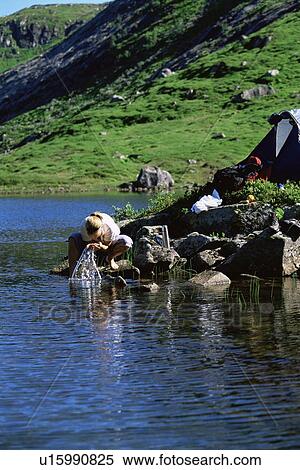 Woman outdoors at campsite washing face in lake View Large Photo Image Stock Photography - Woman outdoors at campsite washing face in lake. Fotosearch